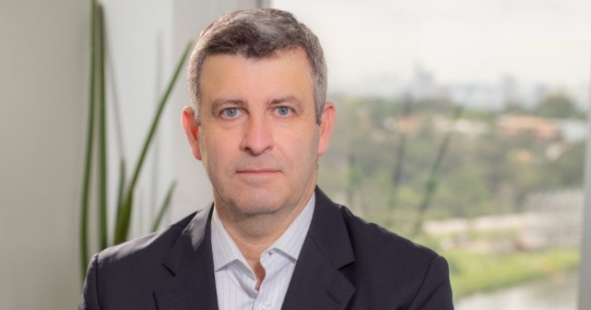 Claudio Tancredi é o novo gerente-geral da Everpure no Brasil 4 Retrato de uma pessoa usando blazer escuro e camisa clara, posicionada de frente para a câmera. Ao fundo há uma janela com vista desfocada para uma área verde e elementos de escritório, incluindo uma planta próxima à janela. A iluminação é suave e natural. (Claudio Tancredi, gerente-geral da Everpure)