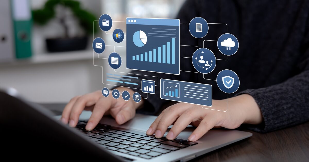 A disputa pela melhor tecnologia começa pela pergunta errada 2 Profissional utiliza notebook com interface digital que reúne gráficos, indicadores, armazenamento em nuvem e recursos de proteção. A imagem representa gestão de cibersegurança, monitoramento, conformidade e administração de serviços de tecnologia. (Brasil, atacado, cibercriminosos)