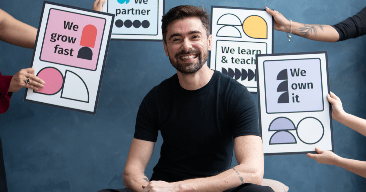Factorial compra startup alemã Empion e integra avaliação de talentos com IA 2 Renan Conde, CEO Brasil da Factorial, posa ao lado de elementos visuais que representam valores da cultura da empresa, como crescimento, colaboração, aprendizado e autonomia.