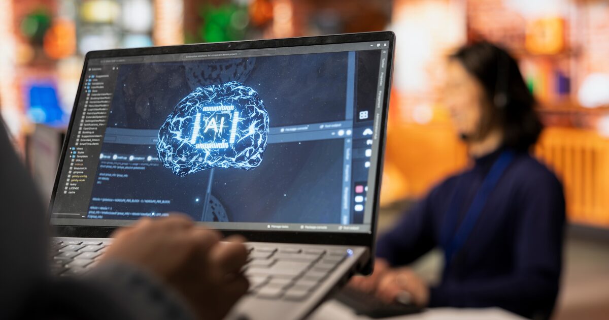 IA em empresas brasileiras: 71% usam, mas só 6% integram processos 2 Pessoa utilizando um notebook com uma representação visual de inteligência artificial na tela, com um cérebro digital conectado a códigos e sistemas tecnológicos. A imagem representa o uso de IA por empresas, transformação digital, inovação e adoção de novas tecnologias no ambiente corporativo.