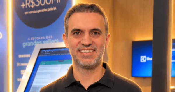 Eduardo Diederichsen, novo general manager da Syonet, empresa do Grupo Webmotors, aparece sorrindo e de braços cruzados durante um evento do setor automotivo, vestindo camisa polo preta com o logotipo da Syonet. Ao fundo, estão o estande da companhia, a identidade visual da marca e participantes do evento desfocados. O executivo assume a liderança da operação após atuar como CTO, com foco na evolução tecnológica e na integração da Syonet ao Grupo Webmotors. (Eduardo Diederichsen, Syonet, Webmotors, Liderança, Tecnologia, Transformação Digital, Mercado Automotivo)